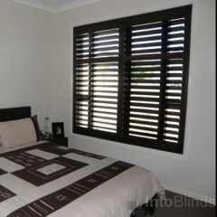 Dark stained Timber plantation shutters in a bedroom setting matching the rooms decor