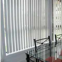 Grey colour Vertical Blinds installed in Living room partially open allowing light to enter the room and retaining privacy.