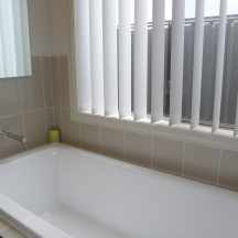 White colour Vertical Blinds installed on 2 windows in Bathroom