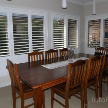 White painted Basswood Timber Plantation Shutters fitted in dining room with teak colour furniture, Location inner suburbs Melbourne Vic