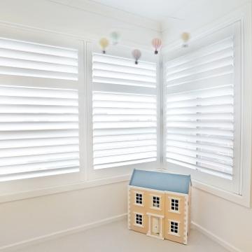 Plantation Shutters fitted to Corner Windows with slats slightly open and panels closed this allows filtered light to enter the room, these have been installed in a bedroom in Melbourne 3000 Vic