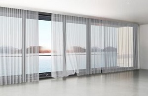 Motorised White Sheer Curtains installed on open sliding doors, wind blowing inwards showing the curtains movement, White ceiling with timber floors, beutifully installed in a lounge room in Melbourne Victoria 3000.